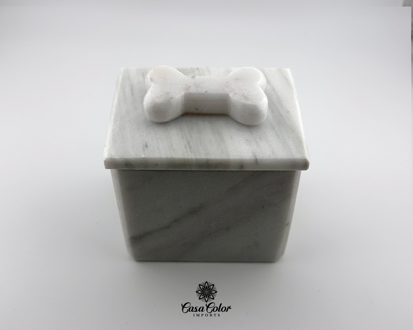 white dog urn for small dogs up to 25 lbs. 3 inches long, 3 inches wide and 3.5 inches high.  Urn is made of white Onyx with soft black veins. The urn has a bone shape on the top of the lid. The urn is square 